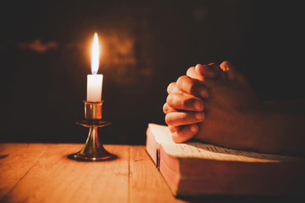 homem orando sobre a biblia na luz velas foco seletivo