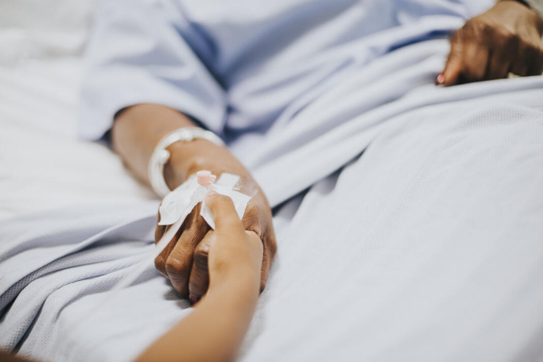 Daughter holding  her mothers hand in the hospital