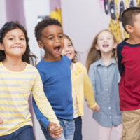 Happy multiracial school children walking thru hallway